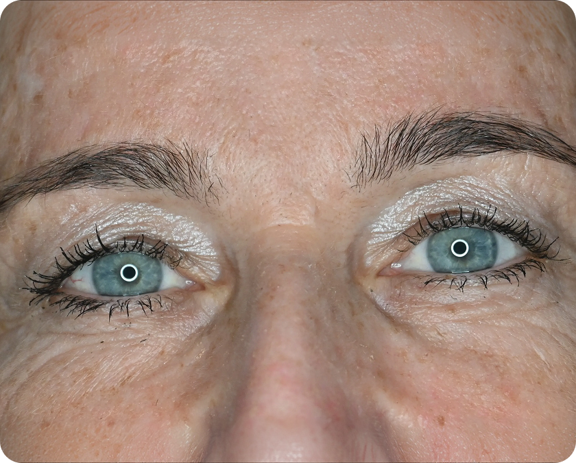 Nahaufnahme der blauen Augen einer Person mit hellem Lidschatten, Wimperntusche und sichtbarer Hauttextur und Poren.