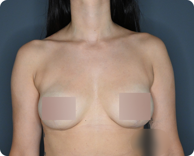 Eine Frau mit langen dunklen Haaren ist von den Schultern aufwärts vor einem grauen Hintergrund abgebildet, wobei ihre Brust aus Gründen der Bescheidenheit teilweise von beigen Rechtecken bedeckt ist.