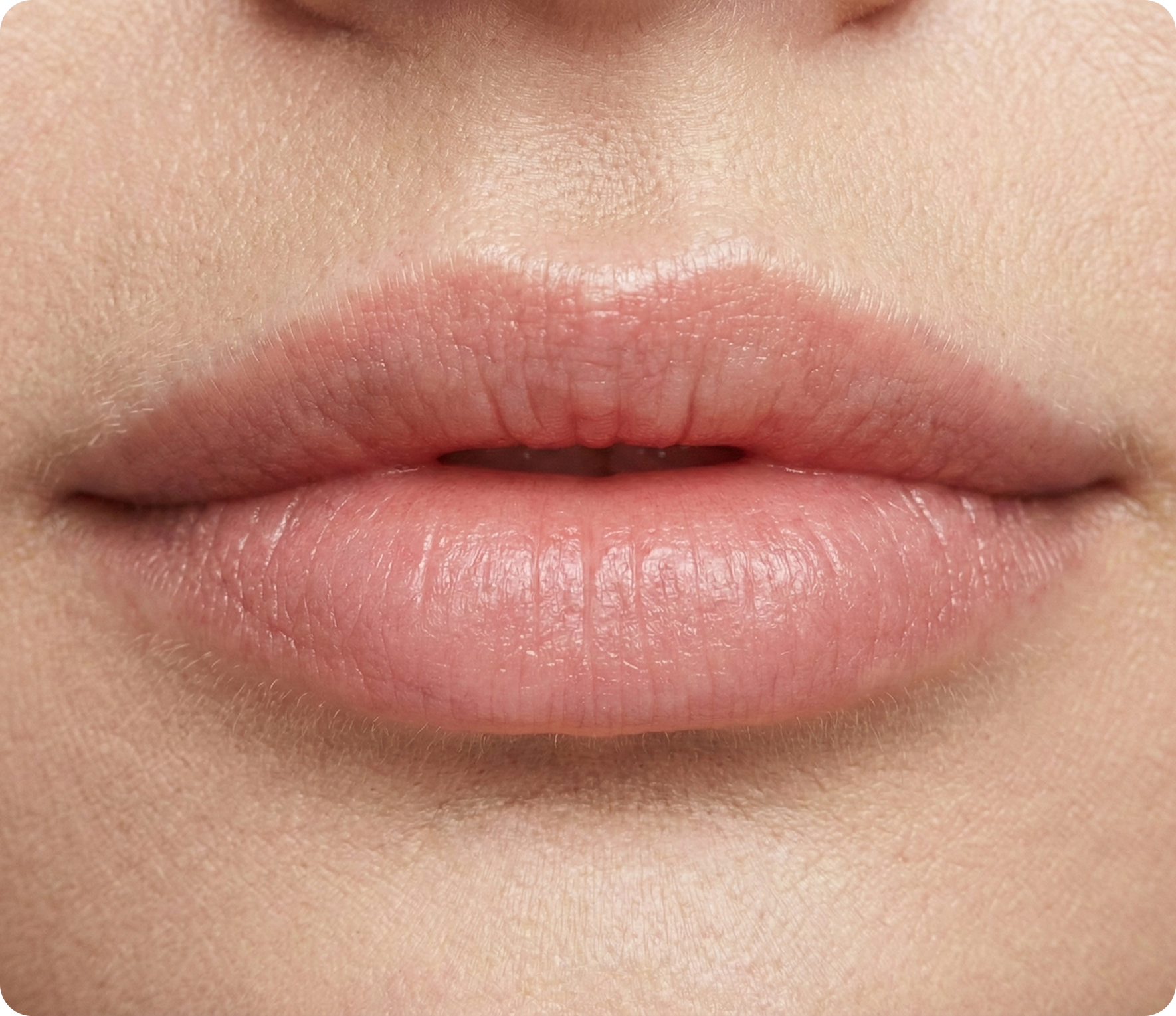 Nahaufnahme der natürlichen, ungeschminkten Lippen einer Person mit neutralem Ausdruck und glatter Haut.